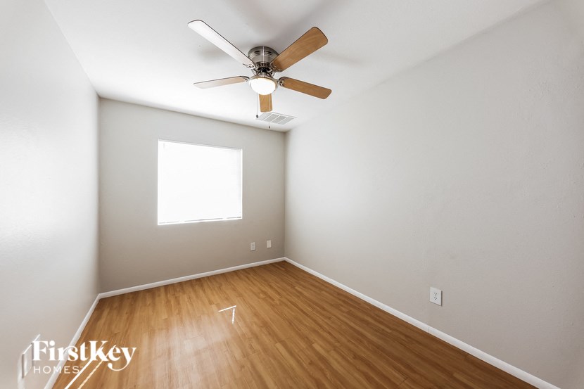 a bedroom with a ceiling fan and wood floors