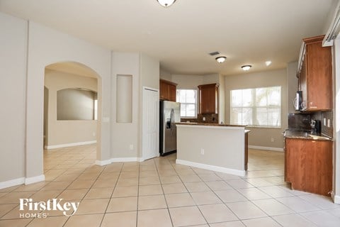 an open kitchen and dining room with white tile flooring and wooden cabinets