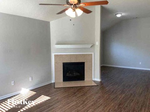 A living room with a fireplace and a ceiling fan.