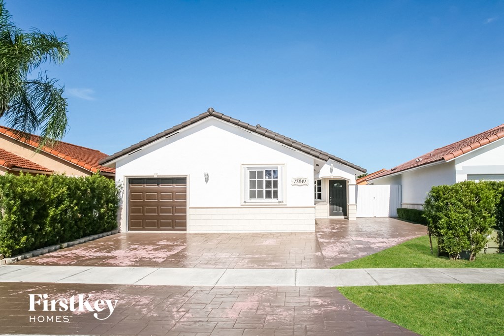 A white house with a brown garage door is for sale.