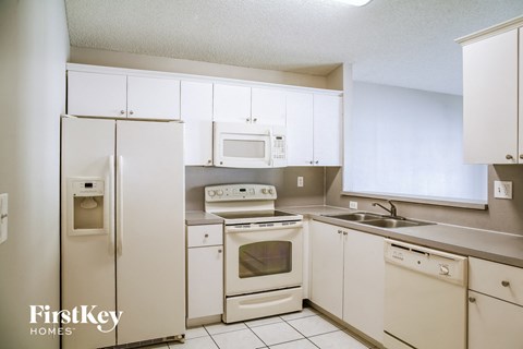 A kitchen with white appliances and cabinets.