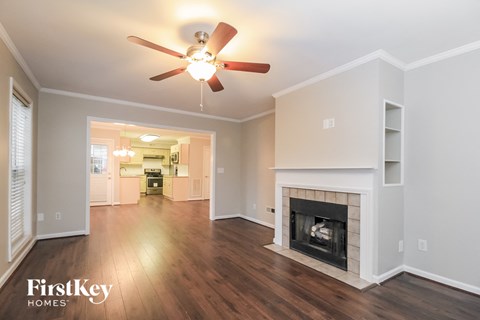 A spacious living room with a fireplace and a ceiling fan.