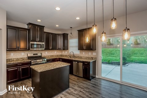 A modern kitchen with dark wood cabinets and a granite countertop.