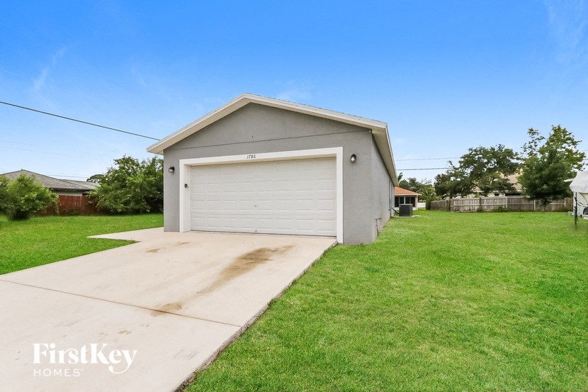 a small gray garage with a white garage door on the grass