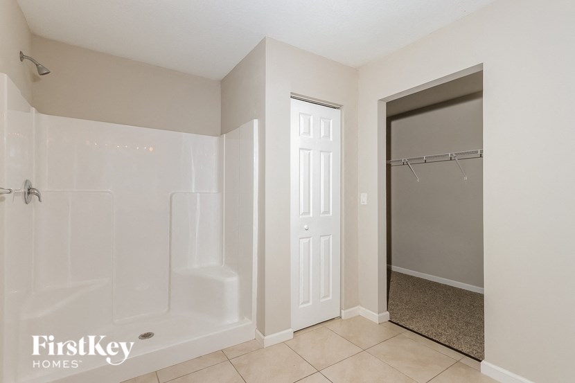 a large bathroom with a shower and a door to the closet