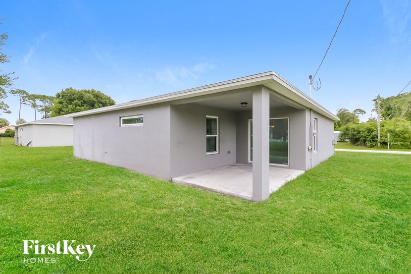 a small gray house with a grass yard and a driveway