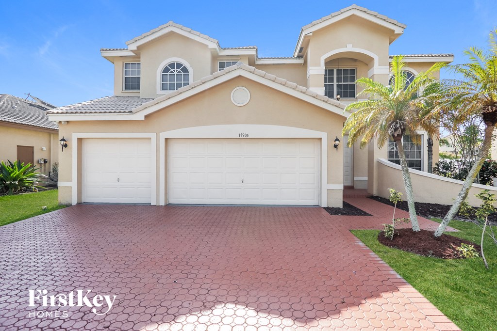 a beige house with a garage door and a palm tree