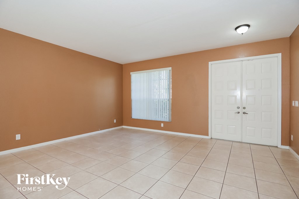 an empty living room with a white tile floor and a white door