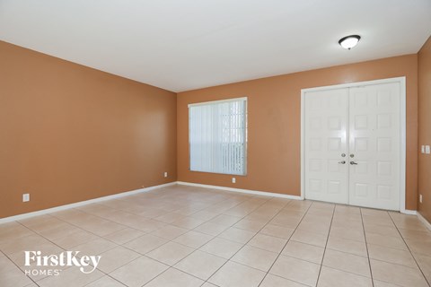 an empty living room with a white tile floor and a white door
