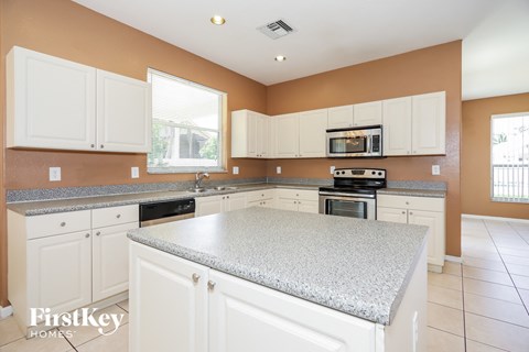 a large kitchen with white cabinets and granite counter tops