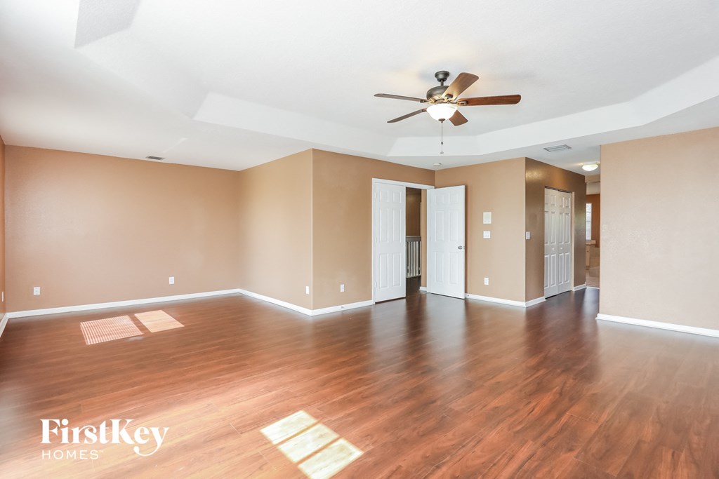 an empty living room with wood floors and a ceiling fan