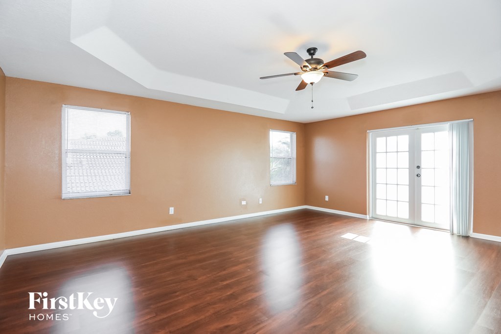 an empty living room with wood floors and a ceiling fan