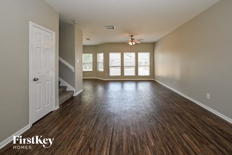 A spacious room with wooden floors and a ceiling fan.