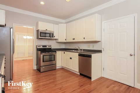 A kitchen with wooden floors and white cabinets.