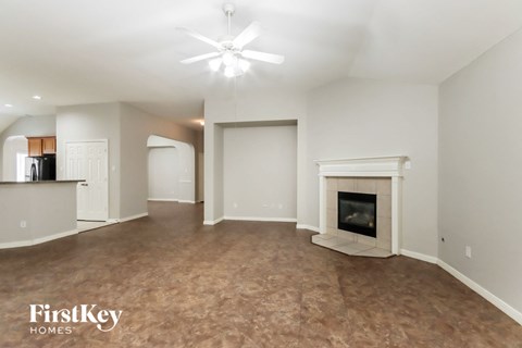 A spacious living room with a fireplace and a ceiling fan.