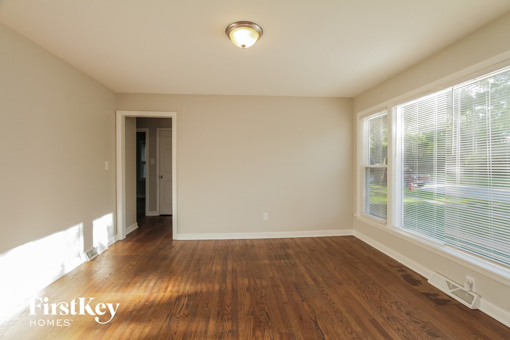 an empty living room with wood floors and large windows