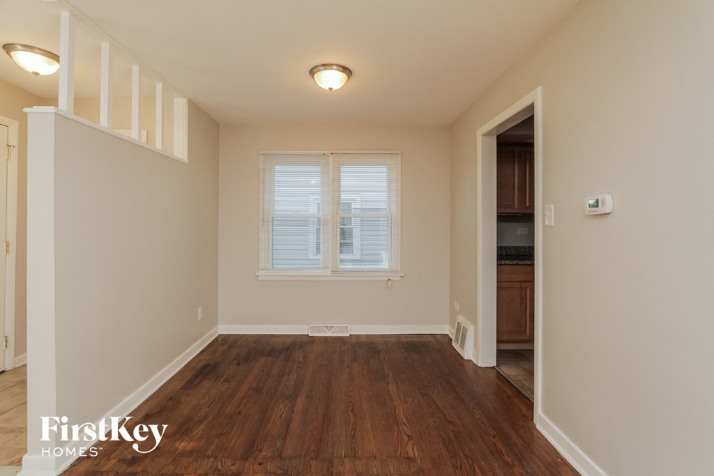 a living room with a hardwood floor and a door to a kitchen