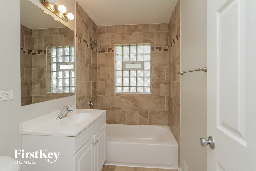 a white bathroom with a tub and a sink and a mirror