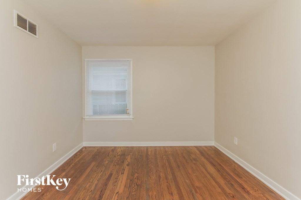 a bedroom with wood floors and a window