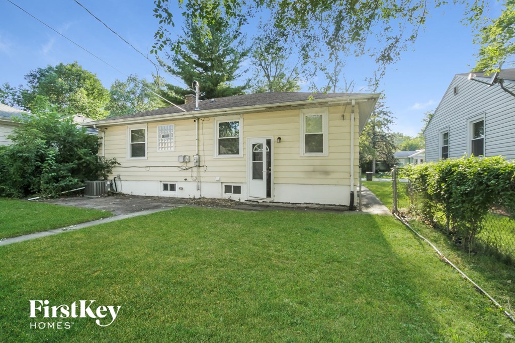 a small yellow house with a lawn and a driveway