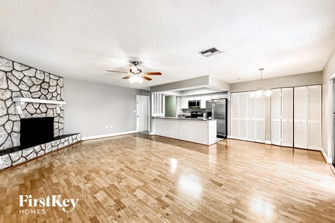 an empty living room with a fireplace and a kitchen