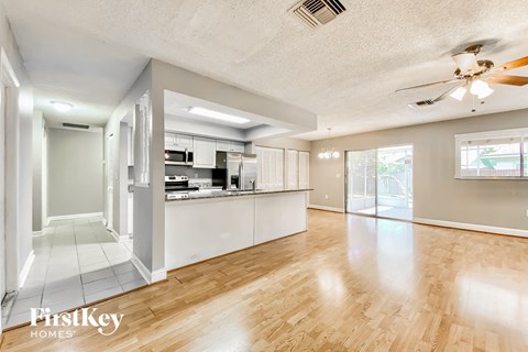 a living room with a kitchen and a ceiling fan