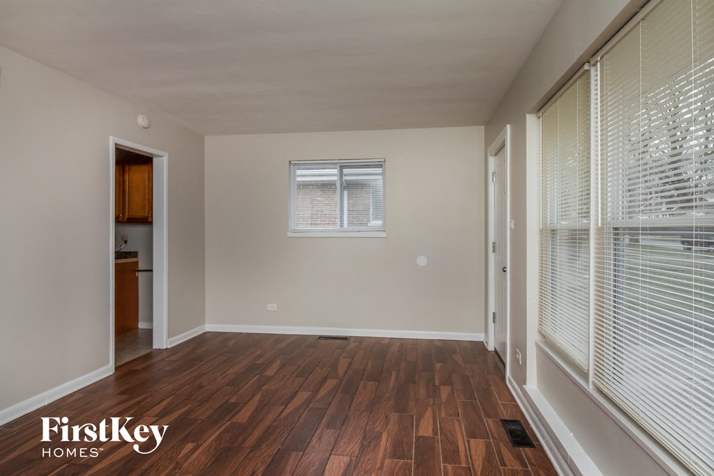 A room with wooden floors and a window with blinds.
