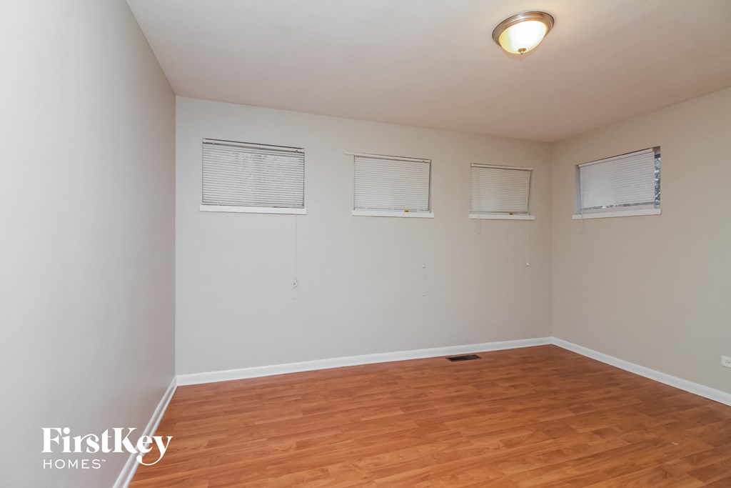 A room with wooden floors and three windows.
