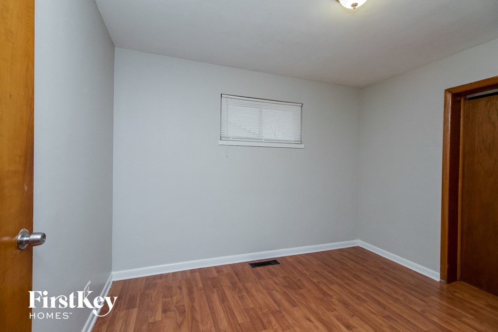 A room with wooden floors and a white wall with a window.