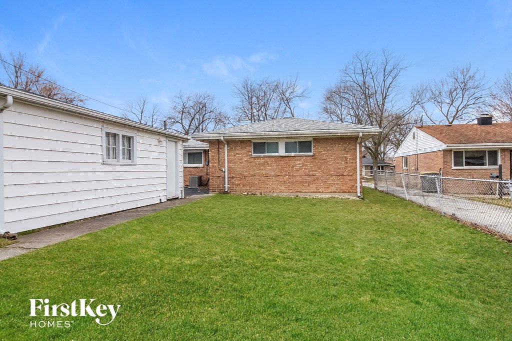 A grassy yard with a house and a fence.