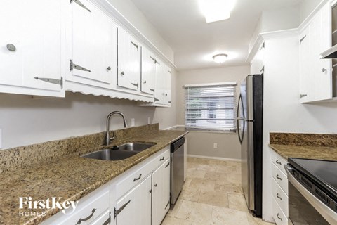 a kitchen with white cabinets and a sink and a refrigerator