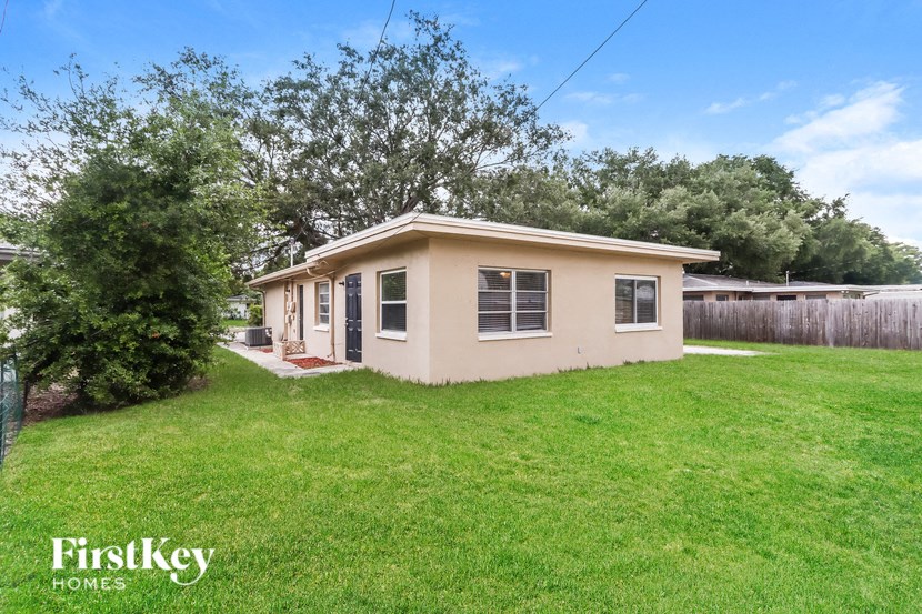 a small beige house with a yard and a tree