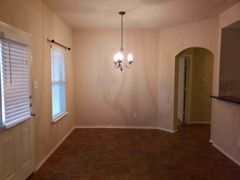 an empty dining room with a chandelier and window