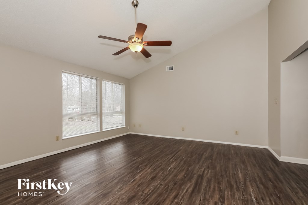 A room with a ceiling fan and wooden flooring.