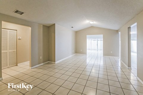 a spacious living room with tiled flooring and a door to the patio