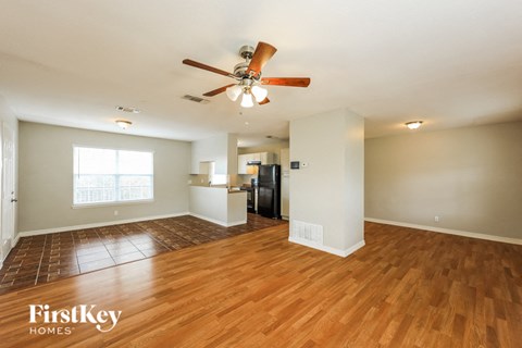 A spacious room with wooden floors and a ceiling fan.