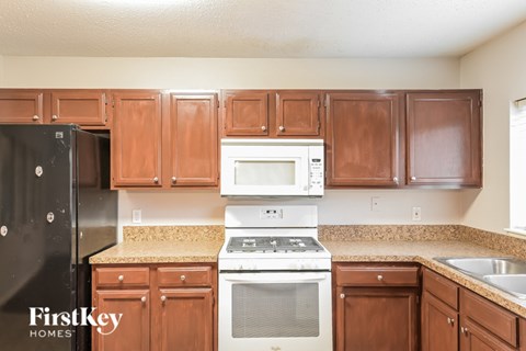 A kitchen with brown cabinets and a black refrigerator.
