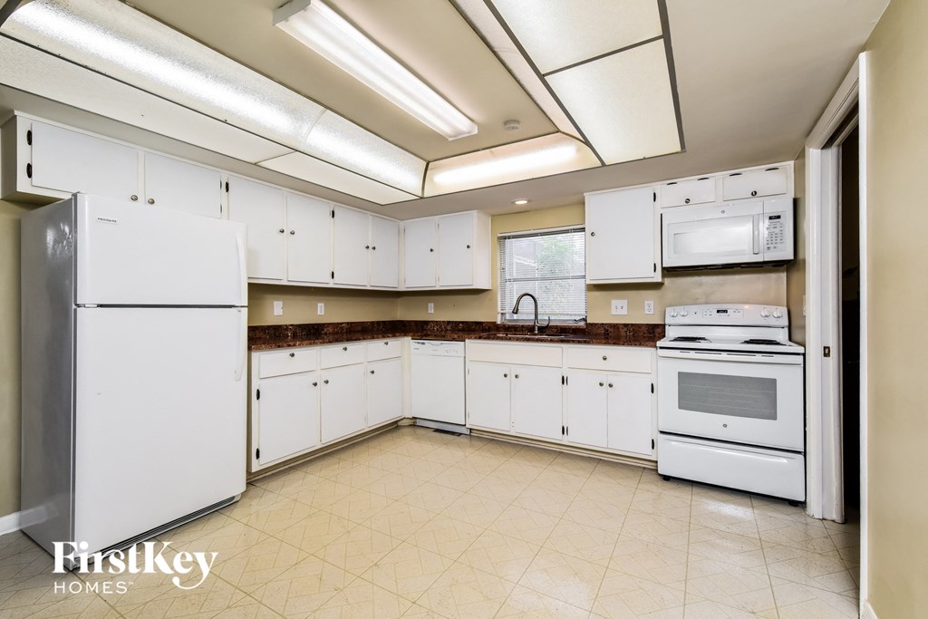 A kitchen with white appliances and cabinets.
