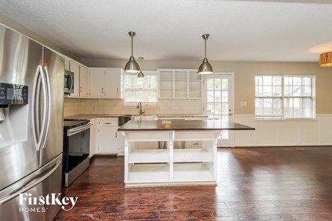 A kitchen with a stainless steel refrigerator and a wooden island.