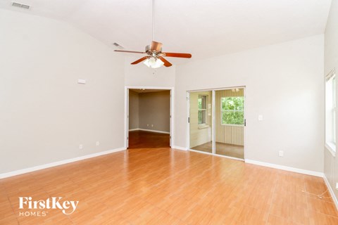 the living room and dining room with wood floors and a ceiling fan