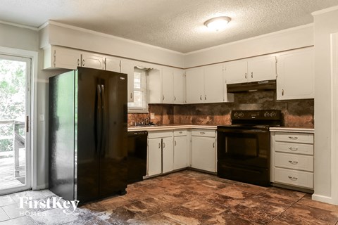 A kitchen with a black refrigerator and white cabinets.