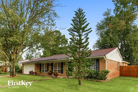 a tree in the yard in front of a house