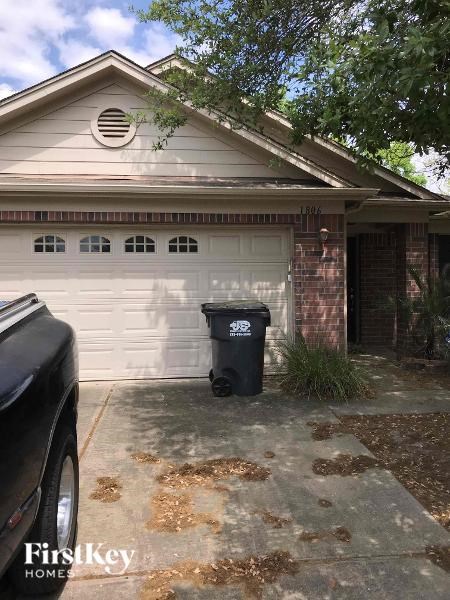 A black trash can sits in front of a garage door.