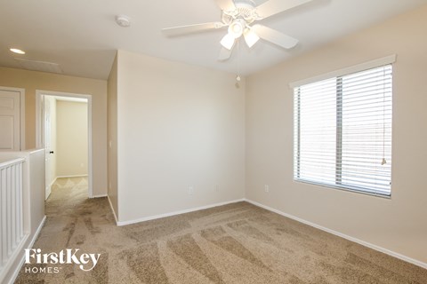 a bedroom with carpet and a ceiling fan and a window