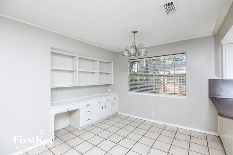 a kitchen with white cabinets and a desk and a window
