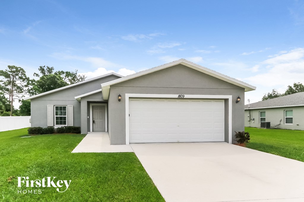 a white house with a garage door and a lawn