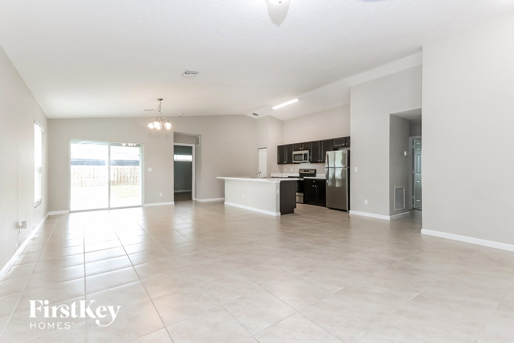 a spacious living room with a kitchen and a large tile floor