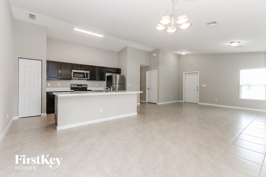 an empty living room with a kitchen and a counter top in the middle