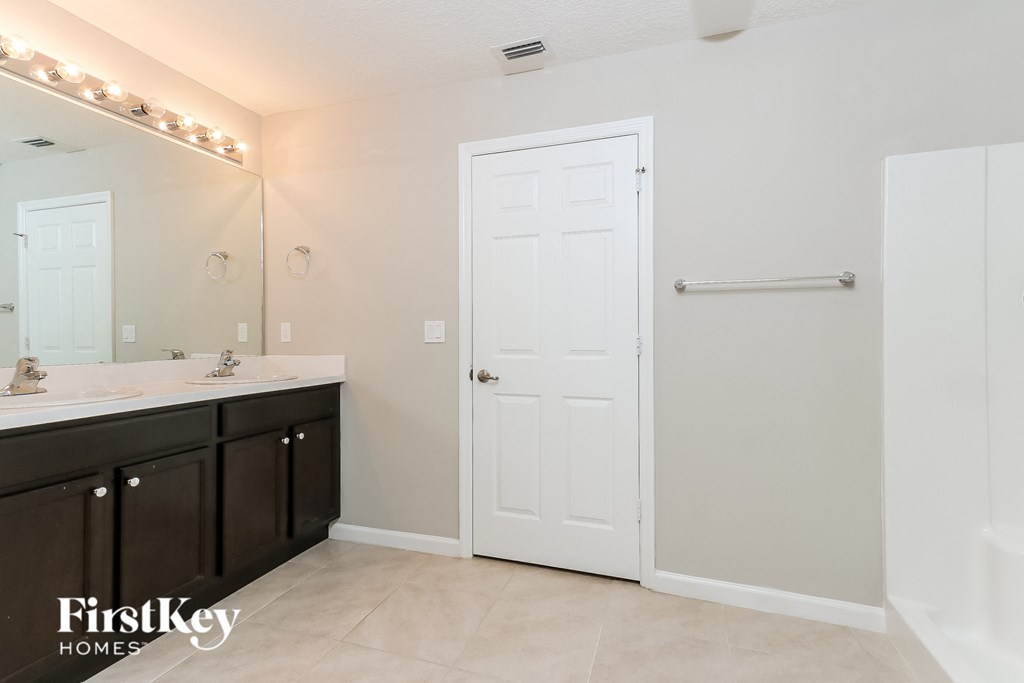 a bathroom with two sinks and a large mirror and a white door