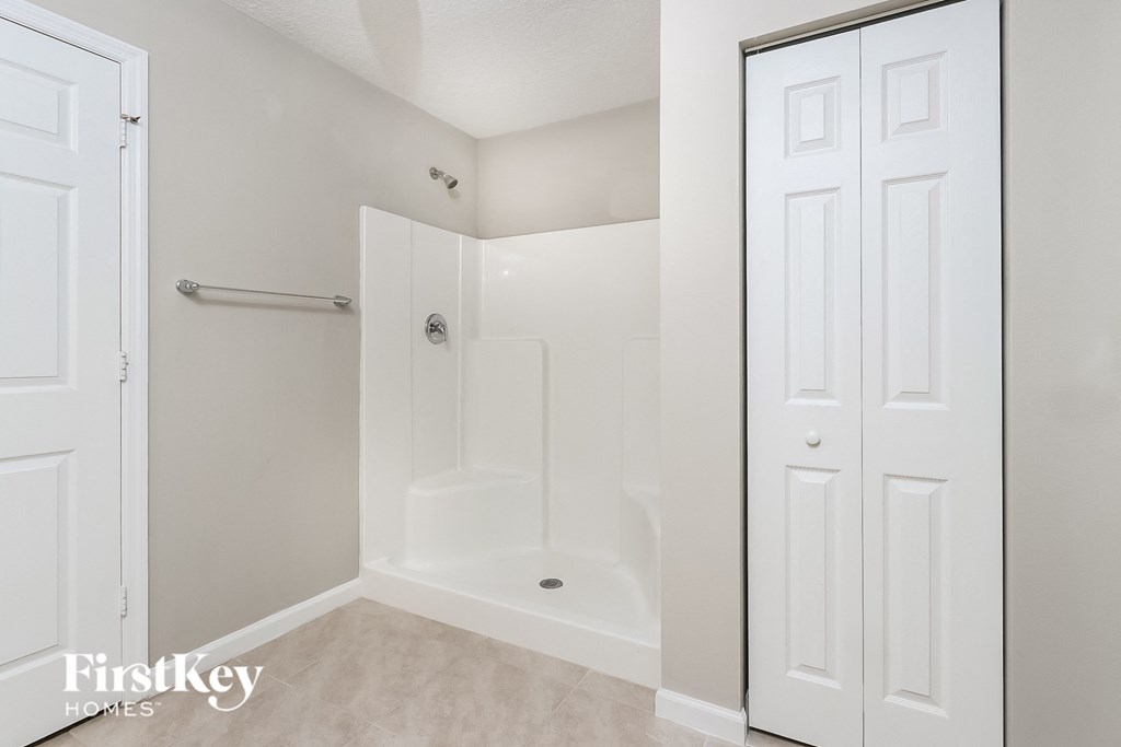 a white bathroom with a shower and a closet